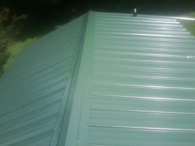 New green metal panels meeting at the ridge of a roof — Flat Roof Repair work by our crew in Cope