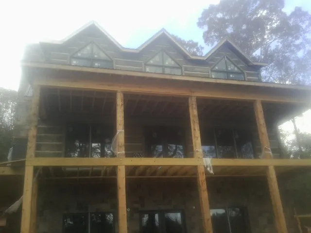 Dormers and porch framing on a large log home under construction — Roof Coating work by our crew in Cope